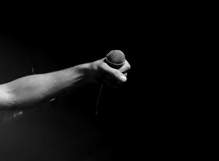 photo d'un bras tenant dans sa main un micro qui signifie la mise en place de l'open mic