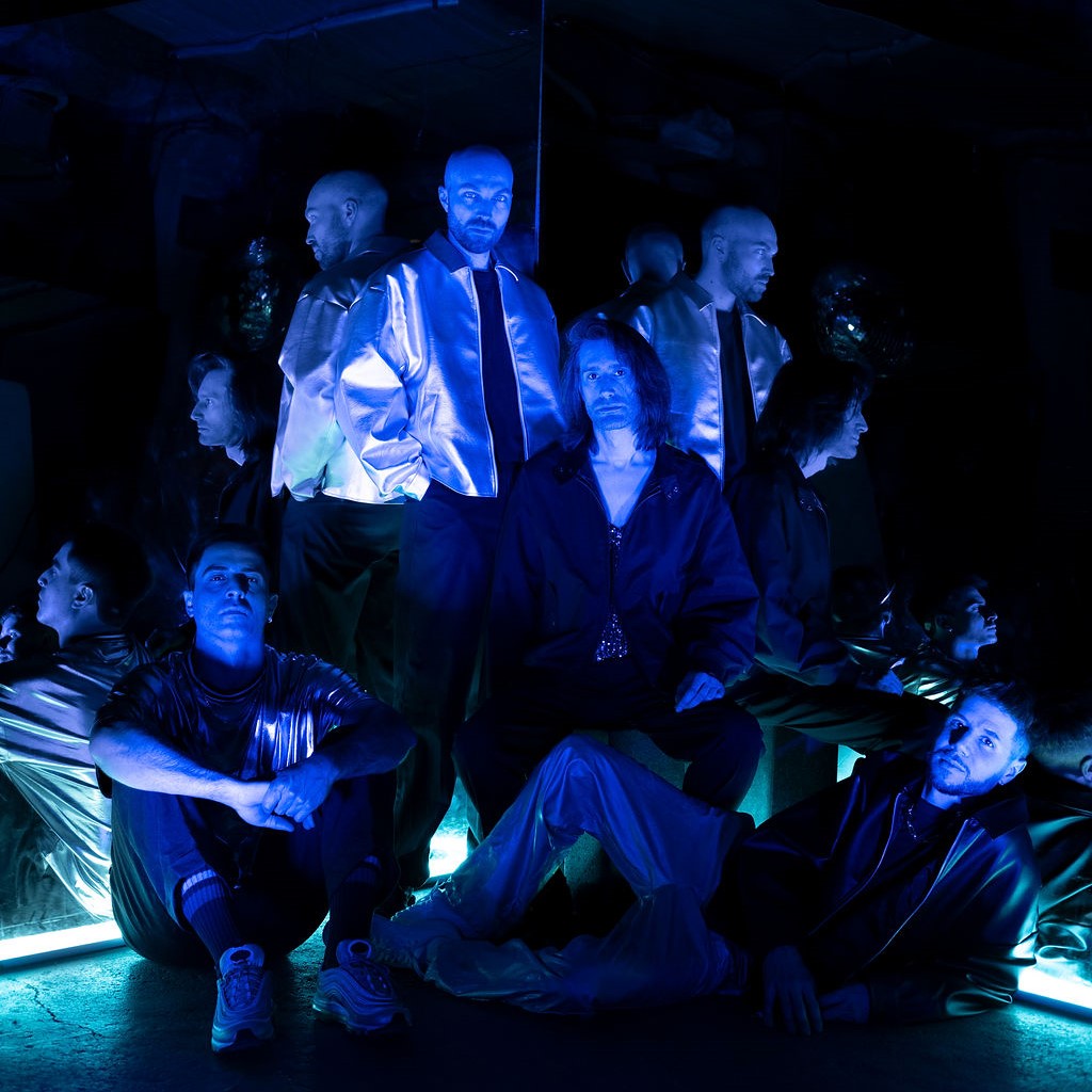 Groupe de Photons pose dans une pièce sombre aux reflets bleus.