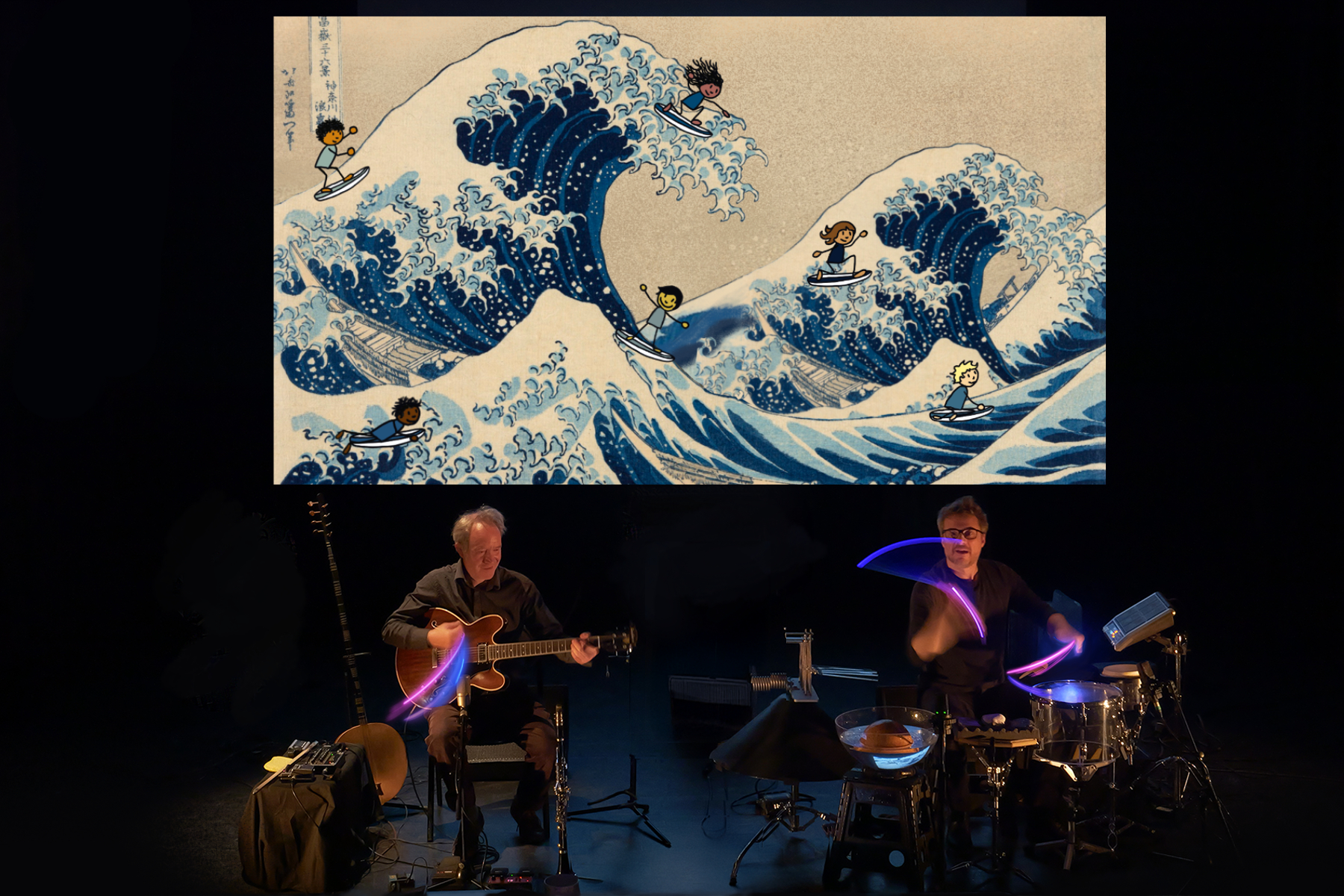Photos du concert : deux musiciens jouent des intstuments : l'un de la guitare et l'autre de la batterie. En fond sur un écran de vidéo projecteur, nous voyons la grande vague de kanagawa.